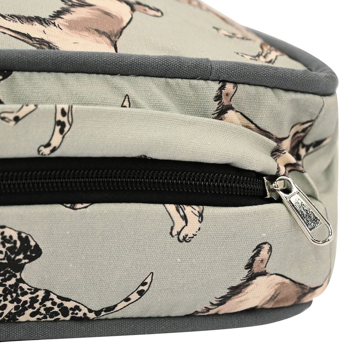 Close-up of a zippered pouch or bag with a light gray fabric printed with dog illustrations in beige, black, and white, featuring a black zipper and silver metal pull.