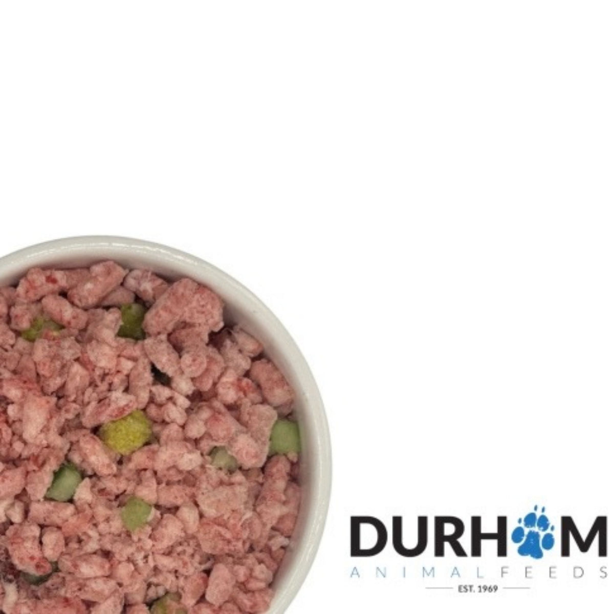 A top-down view of a white bowl filled with raw, pinkish meat-based pet food mixed with small green and yellow pieces, set against a white background with the Durham Animal Feeds logo in the bottom right corner.