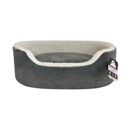 A dark gray pet bed with a light beige fleece lining and a white sherpa trim, featuring a hanging product tag on the right side.