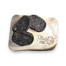 Several pieces of liver cake treats for dogs placed on a wooden surface with a branded stamp that says 'Tilly's Treat Cupboard'.