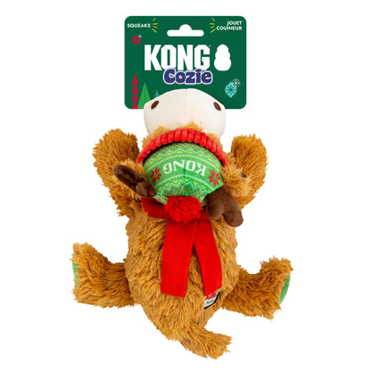 A Kong Cozie plush squeaker dog toy shaped like a brown reindeer, wearing a red and green knitted Christmas sweater, shown on its green retail hanger card against a white background.