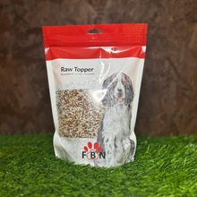 Bag of FBN Raw Topper on grass with a brown background
