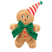 A plush gingerbread man dog toy made of brown sherpa fabric, wearing a red and white striped party hat with a green pom-pom, a large green bow around the neck, and white icing details on a plain white background.