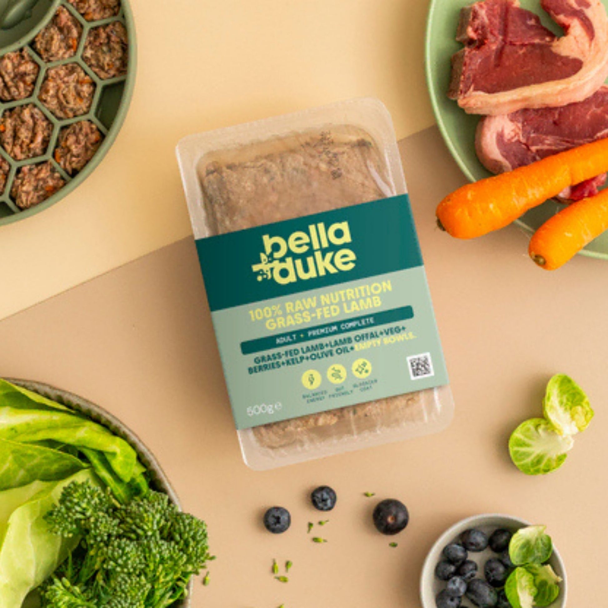 Packaged food with bella+duke label surrounded by fresh produce on a beige background