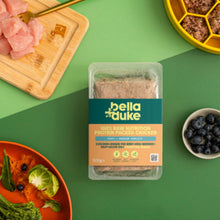 Bella+Duke pet food package on a green background with raw meat and vegetables.
