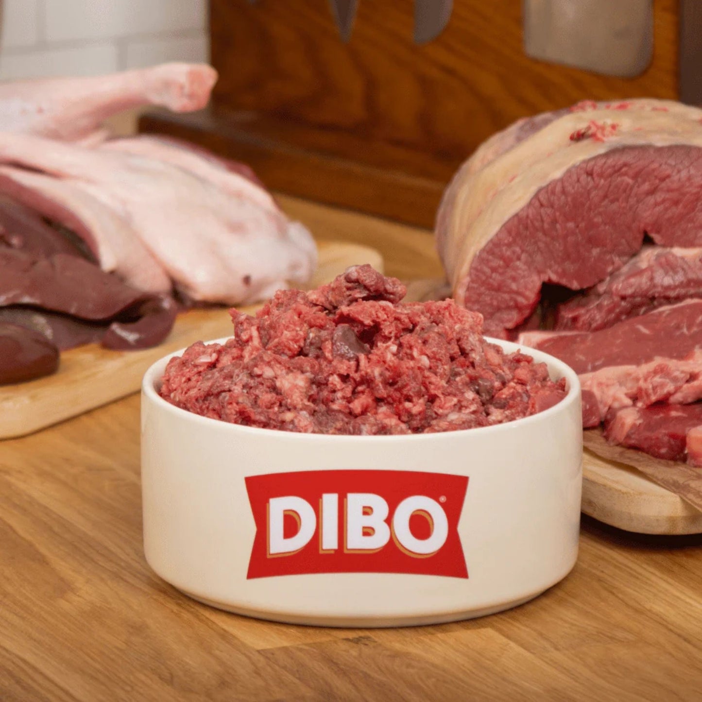 DIBO ground meat in a bowl with raw meat in the background on a wooden surface