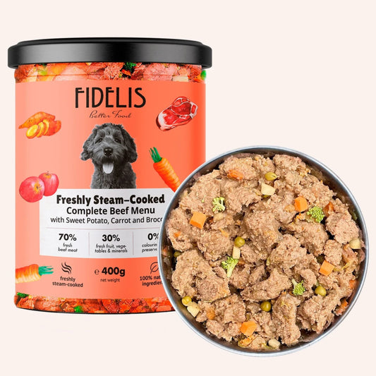A jar of FIDELIS Better For You Freshly Steam-Cooked Complete Beef Menu wet dog food shown next to a metal bowl filled with the prepared food, on a light beige background.