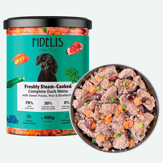 A tub of FIDÉLIS Freshly Steam-Cooked Complete Duck Menu dog food next to a metal bowl filled with the cooked food, on a light gray background.