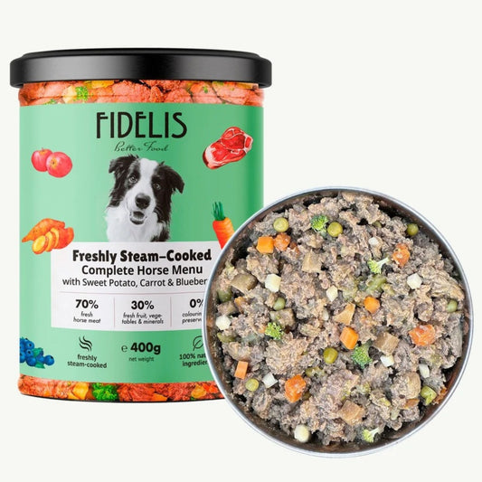 A tub of FIDELIS Freshly Steam-Cooked horse food shown next to a bowl of the prepared food mixture. The label is light green with a picture of a horse and colorful illustrations of vegetables and meat.