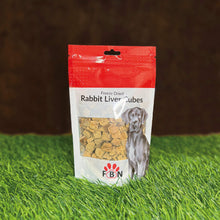 Package of FBN Rabbit Liver Cubes for dogs on grass with a brown background