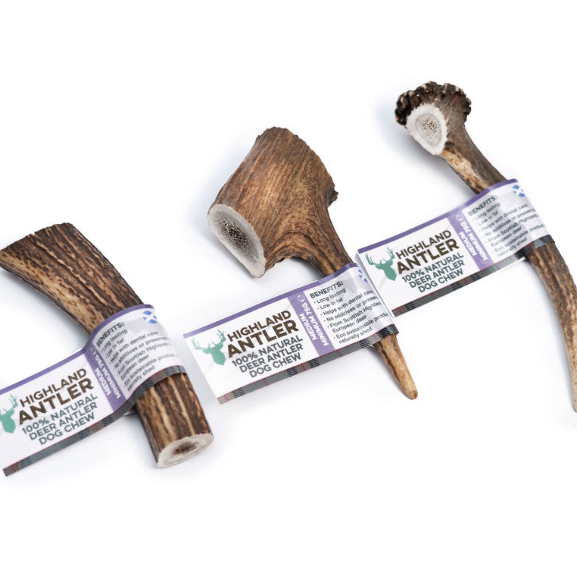 Three Highland Antler 100% natural deer antler dog chews with paper bands, arranged on a plain white background.