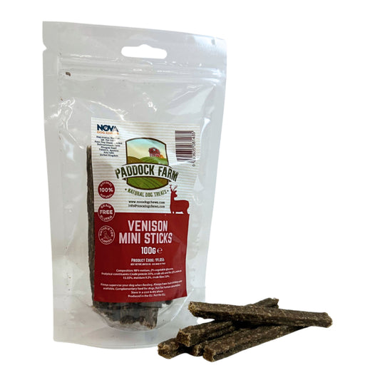 A clear stand-up pouch of Paddock Farm Venison Mini Sticks dog treats with several brown sticks placed in front on a white background.