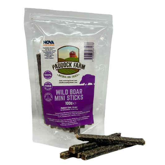 A clear stand-up pouch of Nova Pet Products Paddock Farm Wild Boar Mini Sticks dog treats, with several dark brown treat sticks placed in front on a white background.