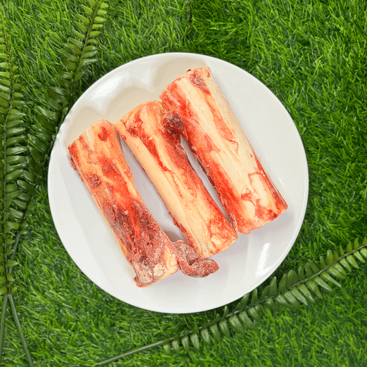 three raw marrow bones on a white plate