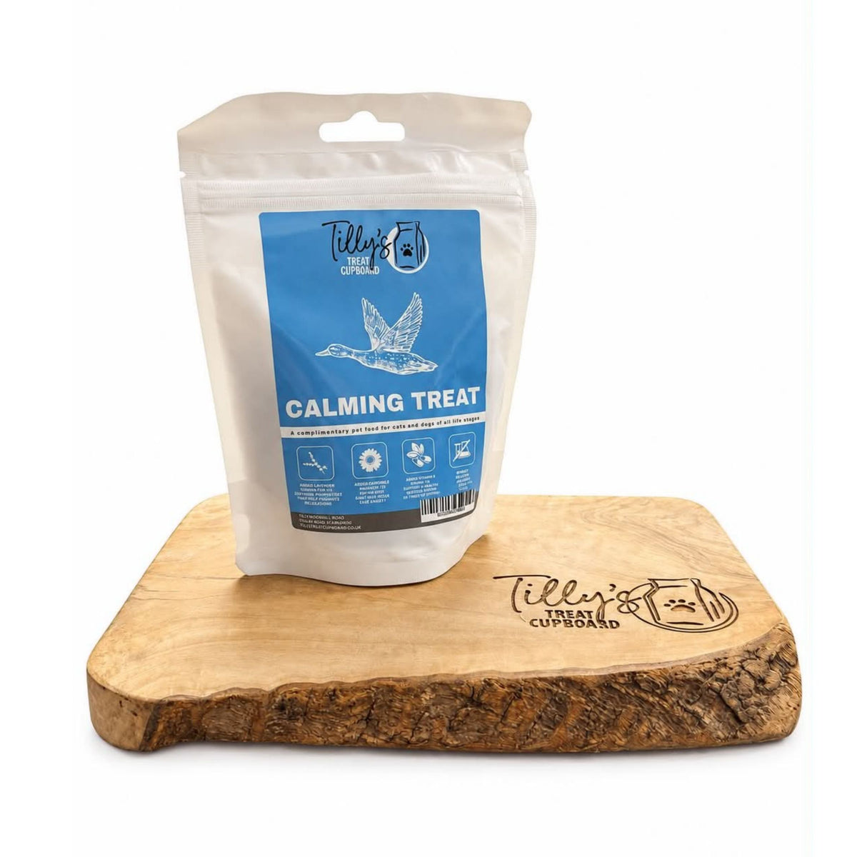 A stand-up pouch of Tilly's Calming Treat for dogs, placed on a rustic wooden serving board with Tilly's branding engraved on it, against a plain white background.