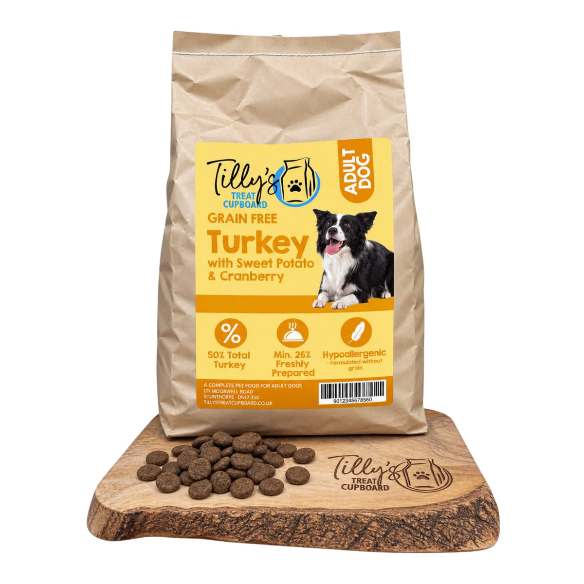 A bag of Tilly's Treat Cupboard Adult Dog grain-free turkey with sweet potato & cranberry kibble stands on a wooden board with loose kibble pieces in front, against a plain white background.