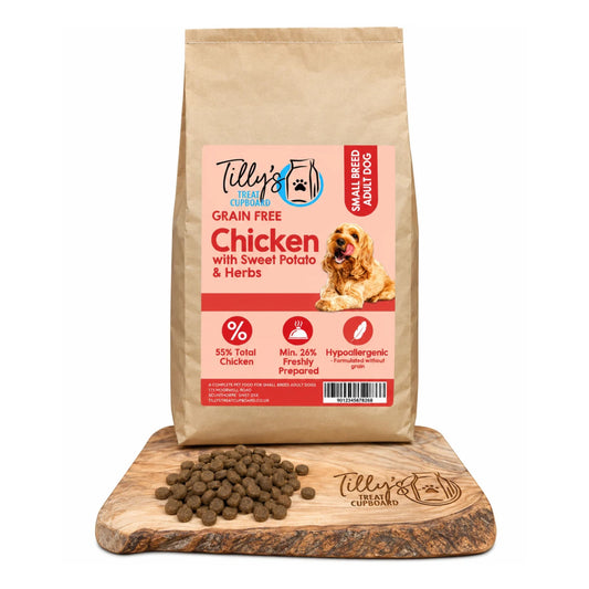 A bag of Tilly's & Tilly's Cupboard Small Breed Adult Dog Grain Free Chicken with Sweet Potato & Herbs dry food, displayed on a wooden cutting board with loose kibble pieces in front, against a white background.