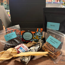 Dog treat box with various treats and labels on a wooden surface