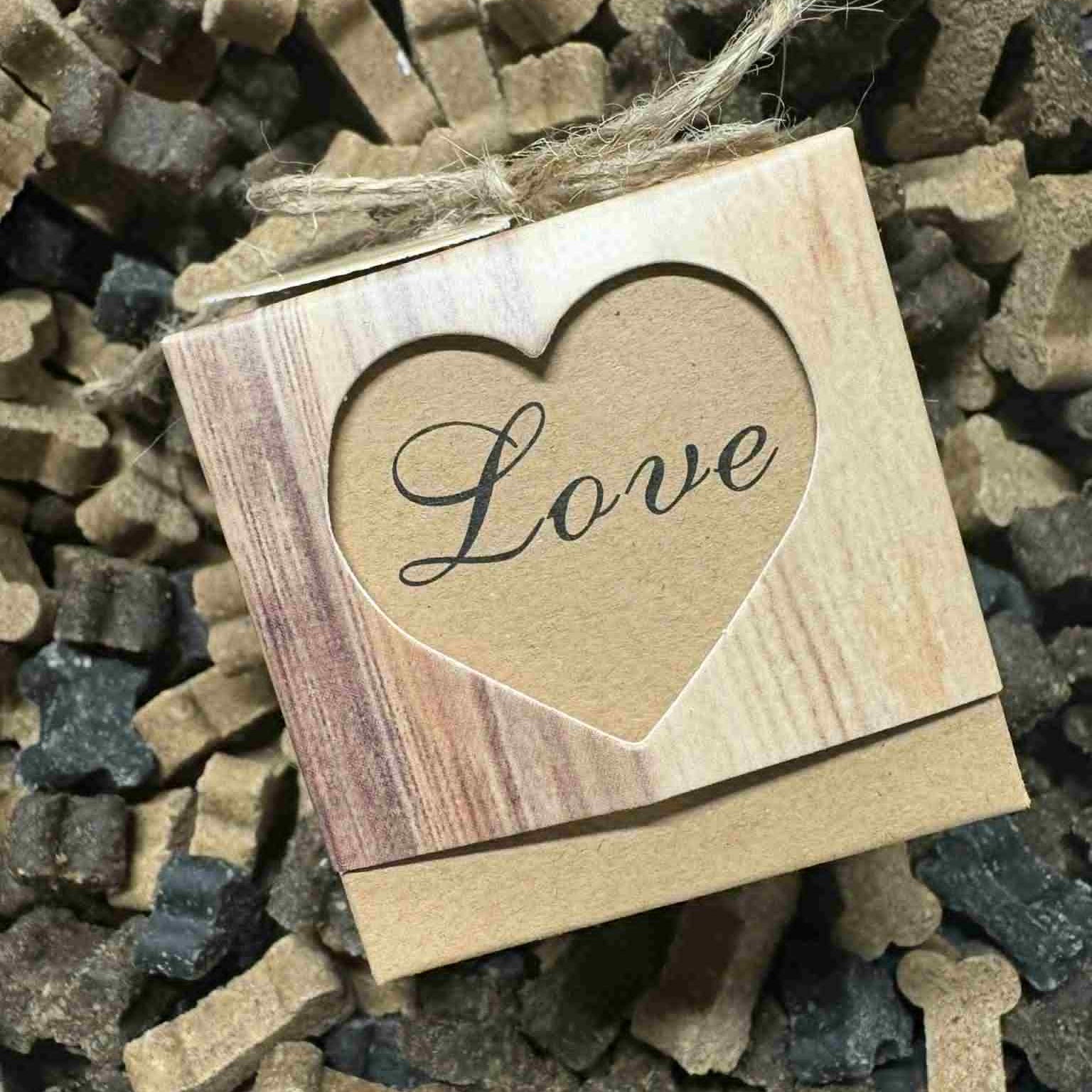 Cardboard treat box with 'Love' printed in a heart shape, surrounded by bone-shaped dog treats.
