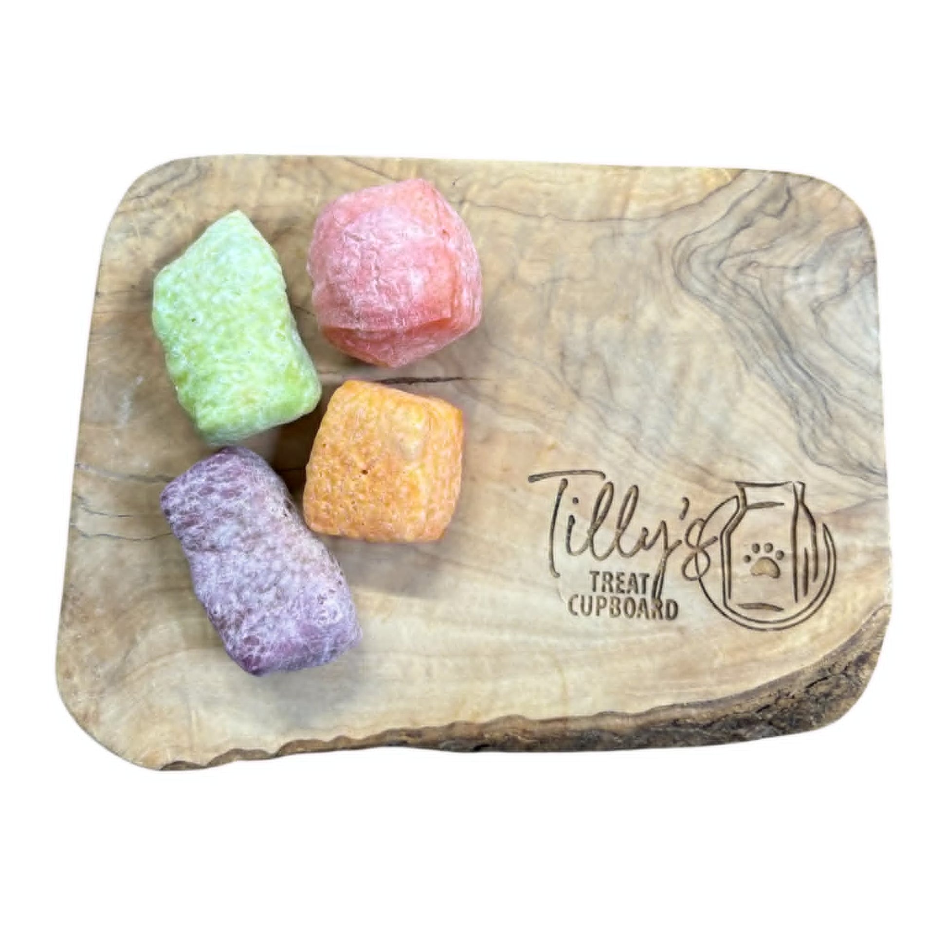 Wooden treat board with colorful dog treats and 'Tilly's Treat Cupboard' branding.